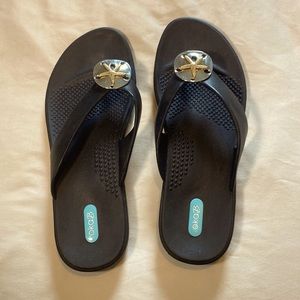 Large black flip flops with sand dollars on them